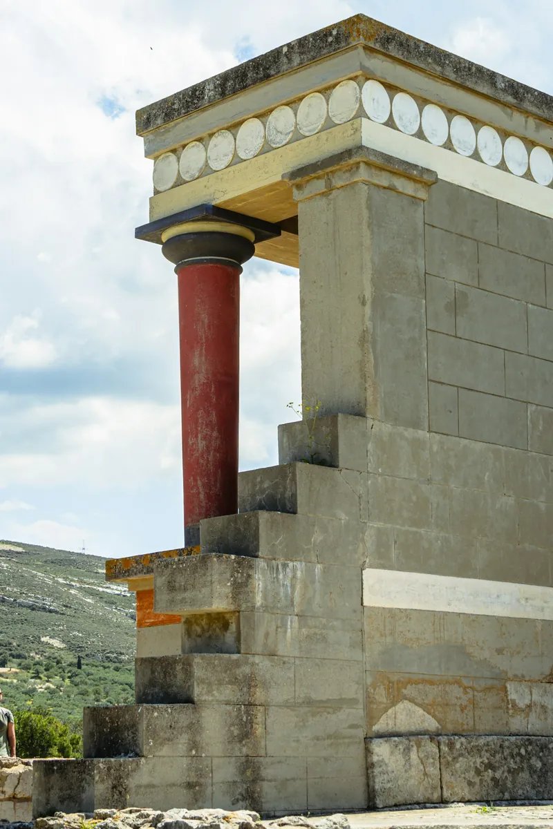 The restored red columns and North Entrance of the Palace of Knossos on Crete, with the charging-bull fresco above the portico